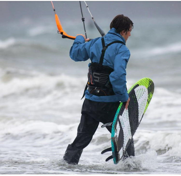 Green Hat Kiteboarding-Drysuit Collection-Ocean Rodeo Soul Drysuit- Kiter walking Into the Water Wearing an Ocean Rodeo Drysuit