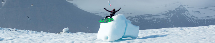 Green Hat Kiteboarding-Winter Wetsuit Collection-Valhalla Artic Kiting by F-ONE/Manera-Man Sitting on an Iceberg with a kiteboard on his Feet and a Kite in the Air