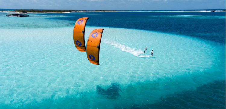 Green Hat Kiteboarding-Duotone Rebel SLS-Inflatable Kite-Red and navy-2 kiters riding on a clear blue ocean