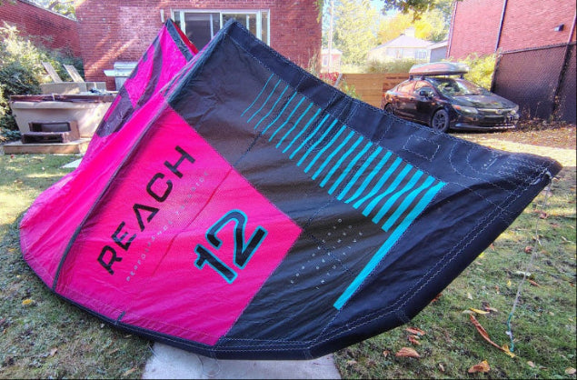 Load image into Gallery viewer, Green Hat Kiteboarding-2024 12m North Reach Kite- Top Right Wing Tip View-Pink kite with 'North' branding on a grassy area with Bag