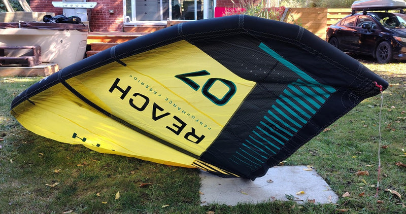 Load image into Gallery viewer, Green Hat Kiteboarding-2024 7m North Reach Kite-Upside Down Left Wing Tip View of Sunset Yellow kite with 'North' branding on a grassy area