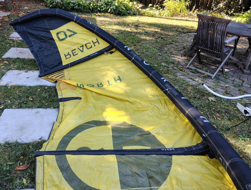 Load image into Gallery viewer, Green Hat Kiteboarding-2024 7m North Reach Kite-Inside Left Wing Tip View of Sunset Yellow kite with 'North' branding on a grassy area
