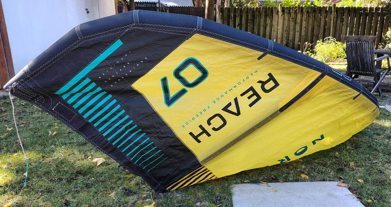 Load image into Gallery viewer, Green Hat Kiteboarding-2024 7m North Reach Kite-Upside Down Right Wing Tip View of Sunset Yellow kite with 'North' branding on a grassy area