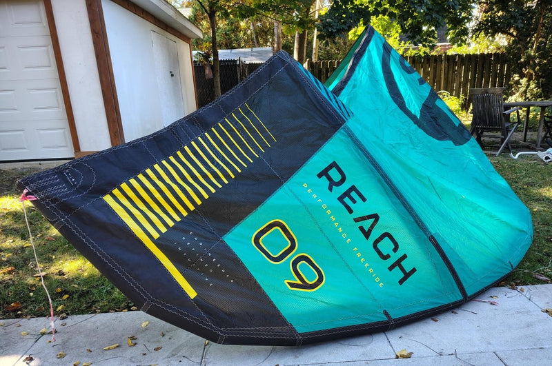 Load image into Gallery viewer, Green Hat Kiteboarding-2024 9m North Reach Kite-Left Wing Tip View of Turquoise kite with 'North' branding on a grassy area