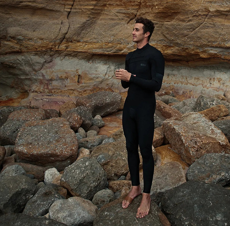 Load image into Gallery viewer, Green Hat Kiteboarding-2025 ION Seek Amp 3/2 FZ Men Wetsuit-Action Shot-Man Wearing ION Wetsuit Standing on Rocks
