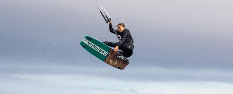 Load image into Gallery viewer, Green Hat Kiteboarding-2025 Cabrinha Ace Wood Core Twin Tip-Action Shot-Woman in the Air Riding a Cabrinha ACE
