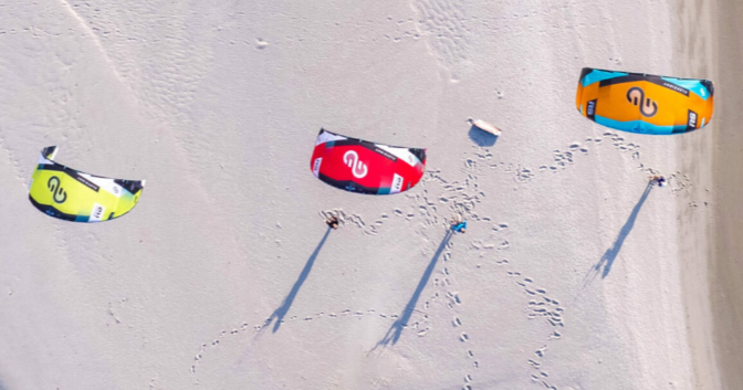 Load image into Gallery viewer, Green Hat Kiteboarding- Eleveight RS V9-Live Shot-Three Eleveight RS in the Air on a Beach