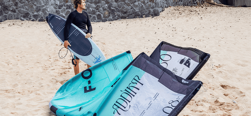 Load image into Gallery viewer, Green Hat Kiteboarding-2025_F-One_Addikt_Kite-Black/Mint-F-One Kite on the Beach next to Pro Rider Keahi holding an F-One Kite Surfboard