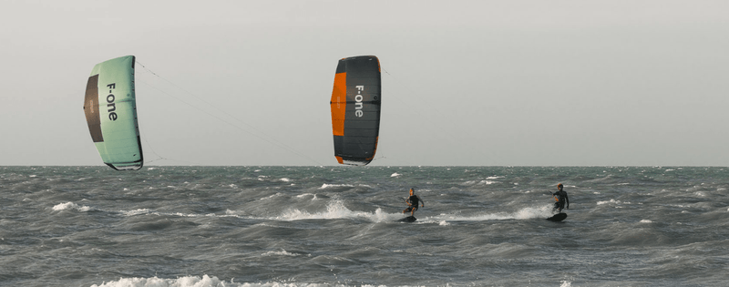 Load image into Gallery viewer, Green Hat Kiteboarding-2025_F-One_Bandit_TEC_Kite-Two Kiters Riding 2025 F-One Bandit TEC Kiteboard Kites of Different Colors