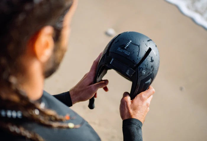 Load image into Gallery viewer, Green Hat Kiteboarding-Mystic Legacy Water Helmet-Live Shot-Man Holding Helmet in his Hands on the Beach