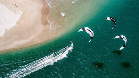 A group of people parasailing on the water with the Core XR7 7m Kiteboarding Kite soaring high in the air.