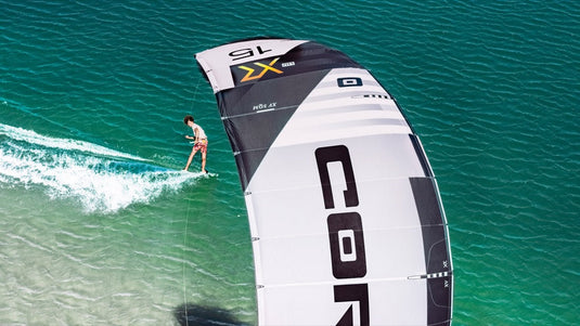A person riding the Core XR7 7m Kiteboarding Kite USED on a surfboard, enjoying windsports and surface water sports.