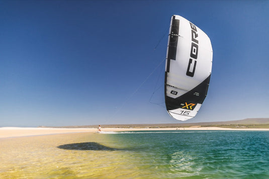 A person on a beach with a kite, flying the Core XR7 7m Kiteboarding Kite.