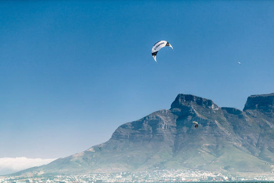 A person flying a kite sports parachute over a mountain landscape with the Core XR7 7m Kiteboarding Kite.