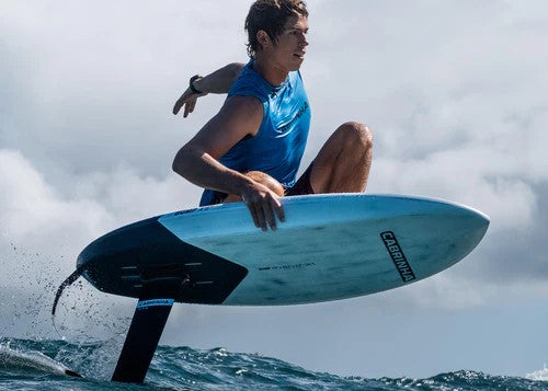 Green Hat Kiteboarding-2024 Cabrinha Bump Prone Foilboard-Man foil surfing on a wave with a cloudy sky background
