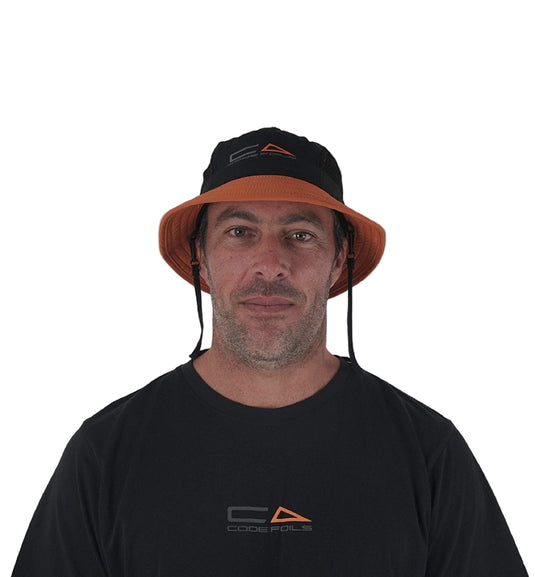 Green Hat Kiteboarding-Code Foils Bucket Hat-Man Looking into the Camera Wearing the Bucket Hat on a White Background