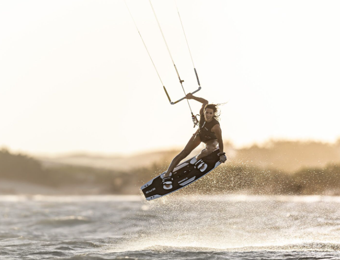 Load image into Gallery viewer, Green Hat Kiteboarding-2025 Core ERA LW Kiteboard-Action Shot-Woman in the Air Riding a Core ERA LW Board