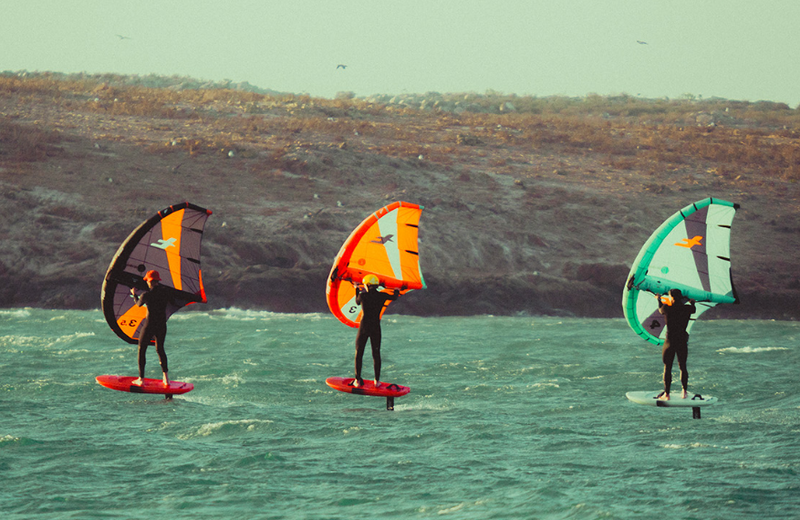 Load image into Gallery viewer, Green Hat Kiteboarding-F-One Strike V4 Wing-Action Shot-Three Men Wing Foiling on the 3 Different Colored F-One Strikes