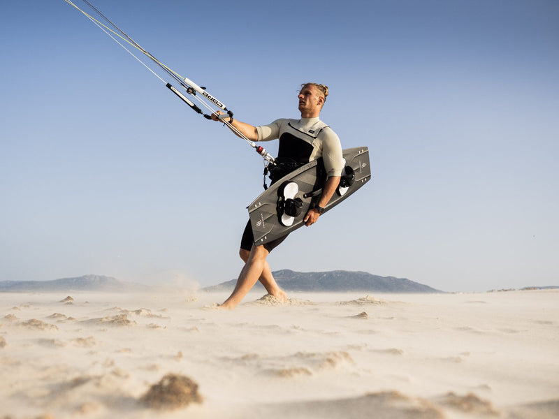 Load image into Gallery viewer, Green Hat Kiteboarding-Carved Imperator PRO-Live Shot-Man Walking on the Beach Holding a Carved Imperator PRO & Flying a Core Kite