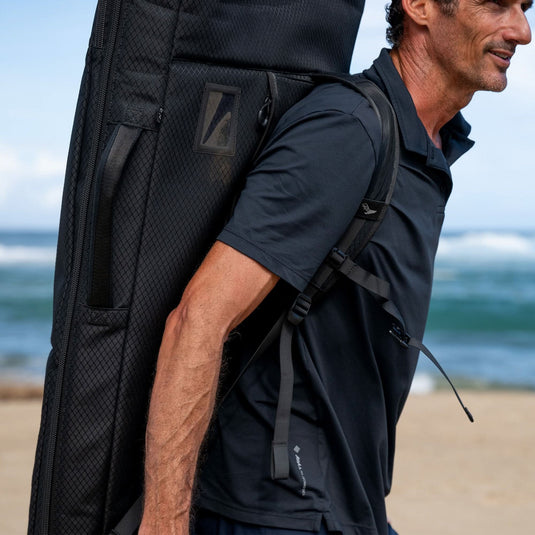 Green Hat Kiteboarding-2025 Lift5 Board Bag-Action Shot-Man Carrying Lift5 eFoil in Black Backpack