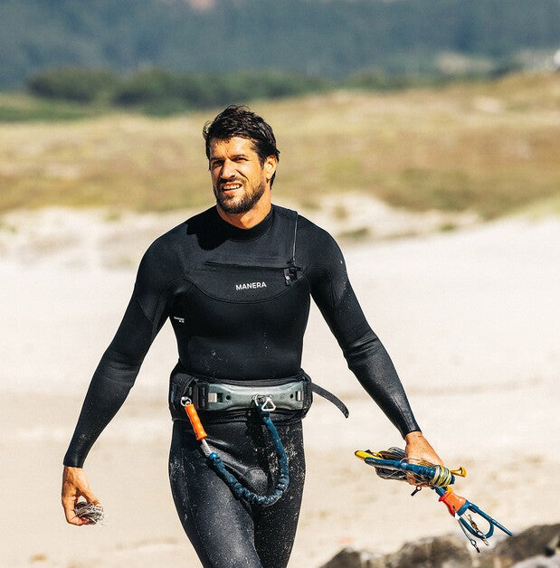 Load image into Gallery viewer, Green Hat Kiteboarding-2026 Manera X10D 3/2 Wetsuit FZ-Live Shot-Man on the Beach Wearing Manera Wetsuit Holding a Kite bar in his Hand