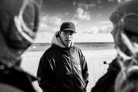 Load image into Gallery viewer, Green Hat Kiteboarding-Mystic Explore LW Poncho-Live Shot-Man Wearing the Poncho on the Beach