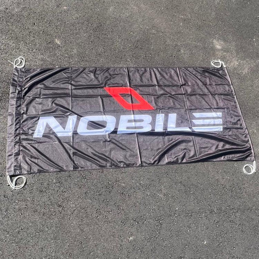 Nobile Kiteboarding Flag USED: a black flag with white text, a white letter on a grey surface, a close-up of a red letter, a close-up of a grey road.