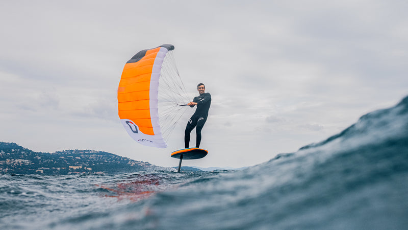 Load image into Gallery viewer, Green Hat Kiteboarding-Ozone Pocket Rocket Parawing-Man parawinging on a foilboard over a body of water.