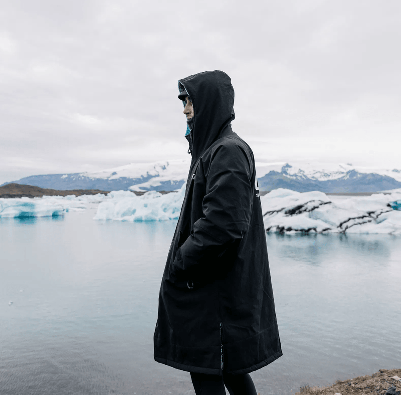 Load image into Gallery viewer, Green Hat Kiteboarding-Ion Storm Coat Worn by Man on the Edge of a Lake with Icebergs