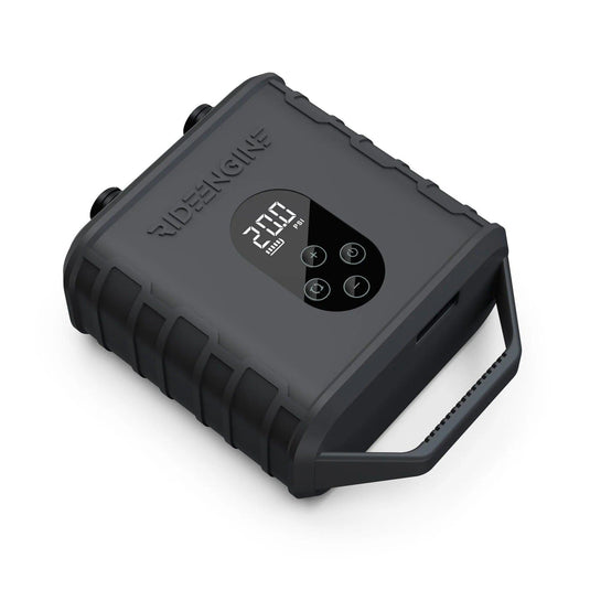 A black device with buttons and a handle, the Ride Engine Air Box Electric Pump, used for inflating kites, wings, and boards. It has a powerful two-stage system for fast inflation and real-time pressure monitoring. Includes Air Box, Hose (3'), 4 Nozzles, USB-C Charging Cable, and 12V Car Charger.