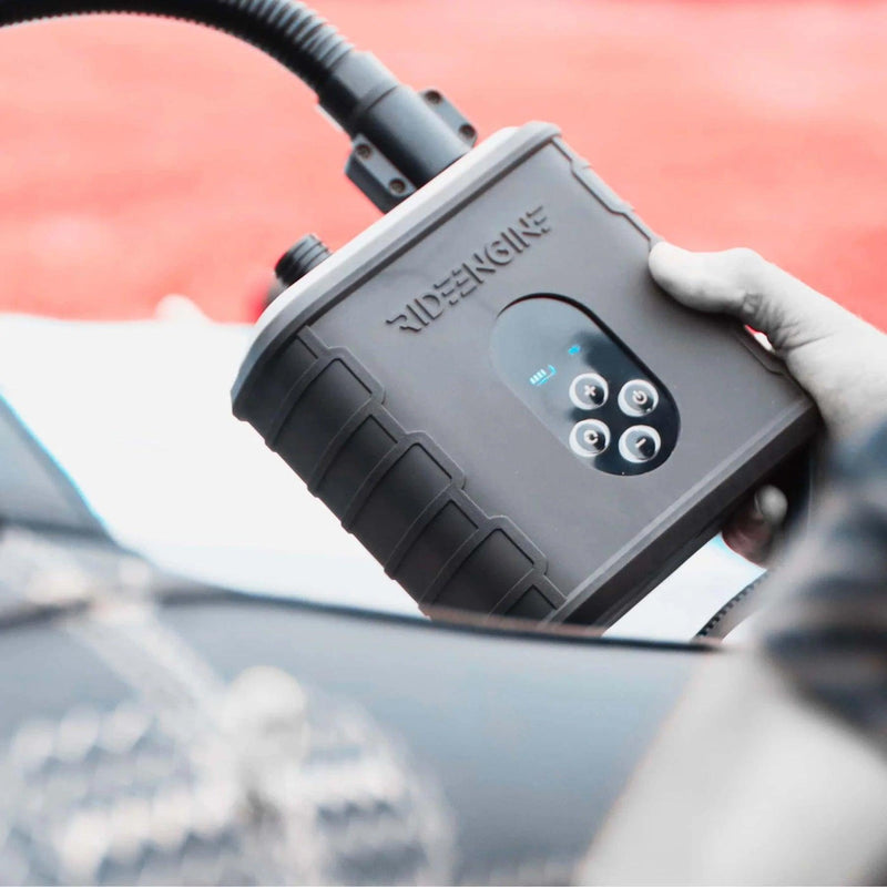 Load image into Gallery viewer, A person holding the Ride Engine Air Box Electric Pump, a rechargeable electric pump for kites, wings, and boards. It has a two-stage system for fast inflation and real-time pressure monitoring.