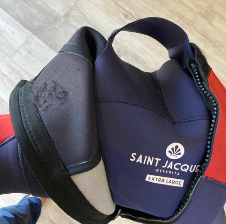 Load image into Gallery viewer, Green Hat Kiteboarding-Saint-Jacques 4/3 BZip Wetsuit USED-Close Up View of Velcro Damage on a Wooden Background
