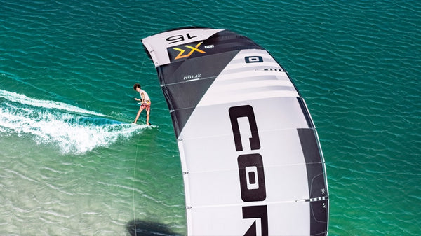 A person riding the Core XR7 Kiteboarding Kite on a kiteboard, enjoying water sports and windsports.