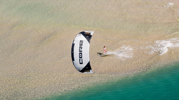 A person on a beach with the Core XR7 Kiteboarding Kite, ready to ride the waves.