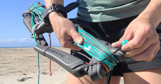 Green Hat Kiteboarding-North Navigator Pro Control bar-Grey and Turquoise Navigator Bar-Held by two hands on the Beach