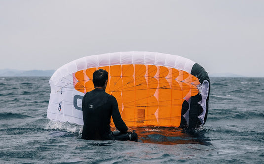 Green Hat Kiteboarding-BLOG-Man Sitting on a Board Flying an Ozone Pocket Rocket