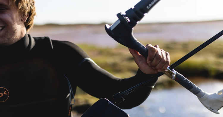 Green Hat Kiteboarding-Cabrinha kiteboarding Control bar-Black and White-Held by a Kiteboarder Wearing a Dakine Wetsuit