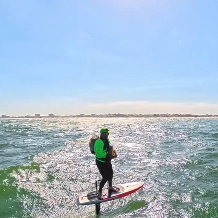Rider foiling hands-free along the New Jersey coast with the wing stowed against the chest