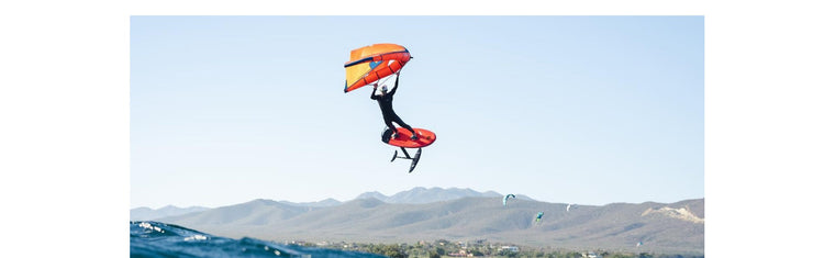 Wing Foiling on F-One wing and board. Orange wing and board. Wing leash, board leash, wetsuit, footstraps