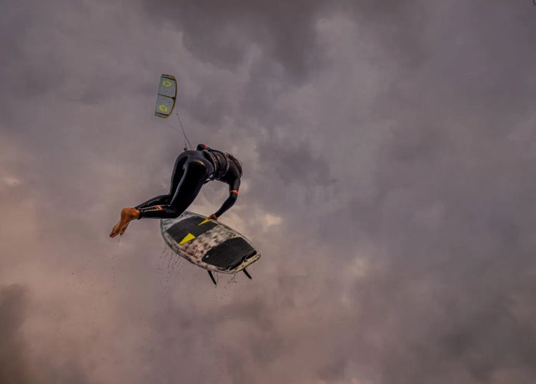 Green Hat Kiteboarding-2025Duotone D/LAB Whip-Kiter in the air doing strapless freestyle with a Duotone Whip in Hand