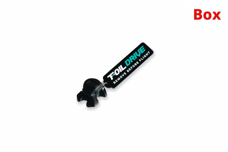 Load image into Gallery viewer, A black plastic keychain-style tool with a small molded black attachment piece and a rectangular tag printed with the brand name 'FOIL DRIVE' in white and teal, plus the text 'REMOVE BEFORE FLIGHT' on a plain white background.
