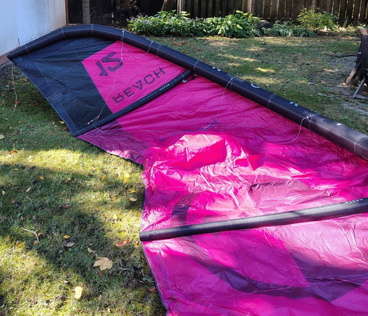 Green Hat Kiteboarding-2024 12m North Reach Kite- Inside Left Wing Tip View-Pink kite with 'North' branding on a grassy area 