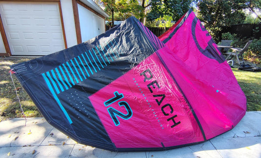 Green Hat Kiteboarding-2024 12m North Reach Kite- Top Left Wing Tip View-Pink kite with 'North' branding on a grassy area with Bag