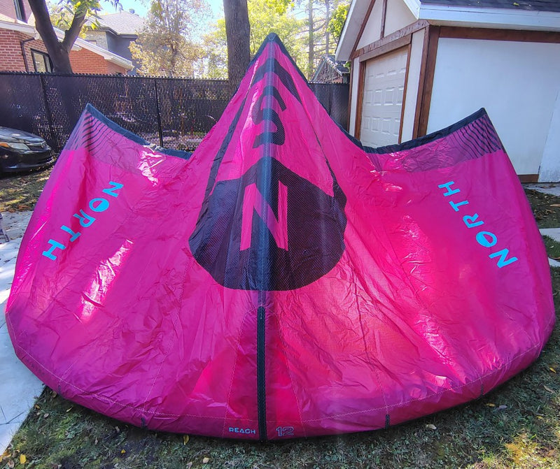Load image into Gallery viewer, Green Hat Kiteboarding-2024 12m North Reach Kite-Pink kite with &#39;North&#39; branding on a grassy area without Bag
