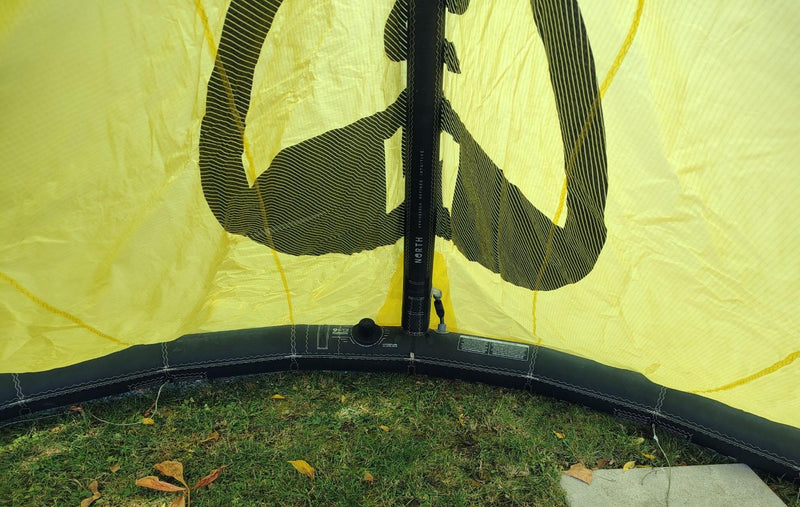 Load image into Gallery viewer, Green Hat Kiteboarding-2024 7m North Reach Kite-Close Up View of Valve and Center Strut of Sunset Yellow kite with &#39;North&#39; branding on a grassy area 
