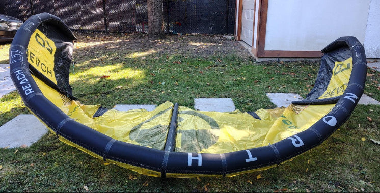 Load image into Gallery viewer, Green Hat Kiteboarding-2024 7m North Reach Kite-Upside Down Leading Edge View of Sunset Yellow kite with &#39;North&#39; branding on a grassy area 
