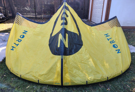 Green Hat Kiteboarding-2024 7m North Reach Kite-Sunset Yellow kite with 'North' branding on a grassy area without Bag