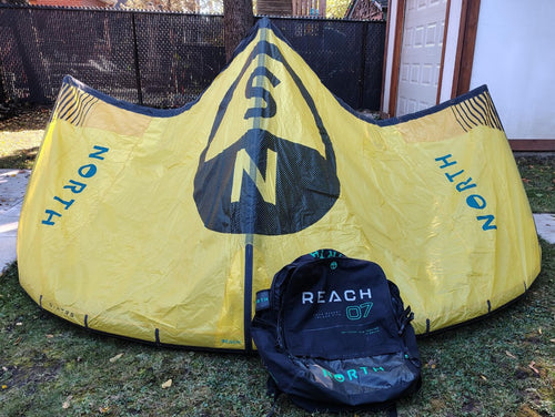 Green Hat Kiteboarding-2024 7m North Reach Kite-Sunset Yellow kite with 'North' branding on a grassy area with Bag