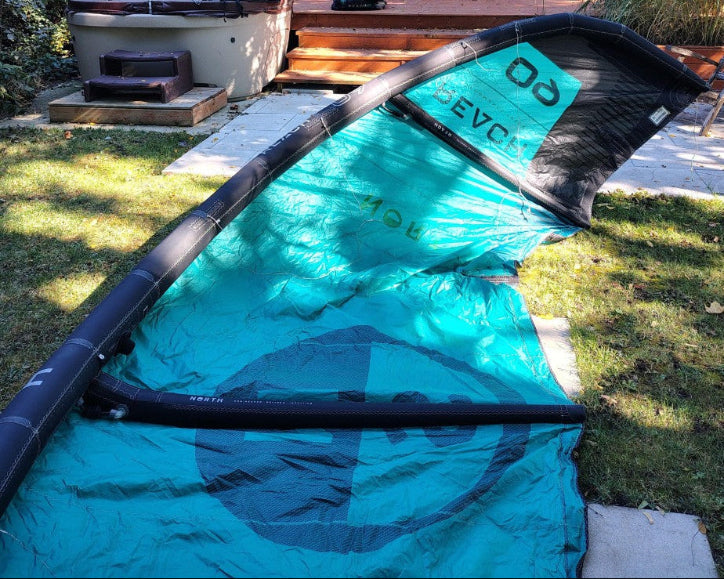 Load image into Gallery viewer, Green Hat Kiteboarding-2024 9m North Reach Kite-Inside Right Wing Tip View of Turquoise kite with &#39;North&#39; branding on a grassy area
