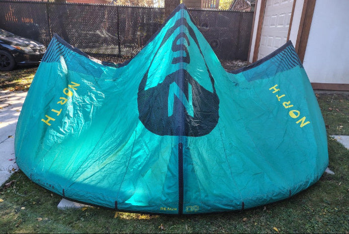 Load image into Gallery viewer, Green Hat Kiteboarding-2024 9m North Reach Kite-Turquoise kite with &#39;North&#39; branding on a grassy area without Bag
